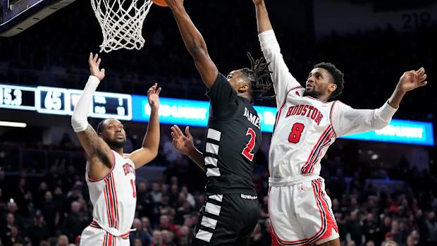 Cincinnati Bearcats guard Jizzle James (2) rises to the basket as Houston Cougars guard Mylik Wilson (8) defends in the second half of an NCAA college basketball game between the Houston Cougars and the Cincinnati Bearcats, Saturday, Feb. 10, 2024, at Fifth Third Arena in Cincinnati.